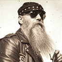 Ein altes Foto von Karl Auer. Er Trägt Lederkleidung, Sonnenbrille, Lederkappe, und hat einen langen grauen Bart